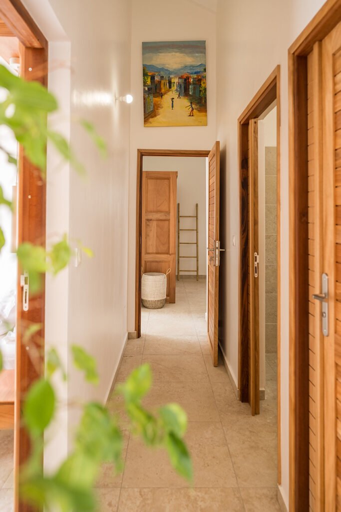 Couloir avec portes en bois et plante verte qui mêne aux chambres et à la salle de bain de la Villa Residence Raisins Clair Guadeloupe Sainte Francois West Indies 97